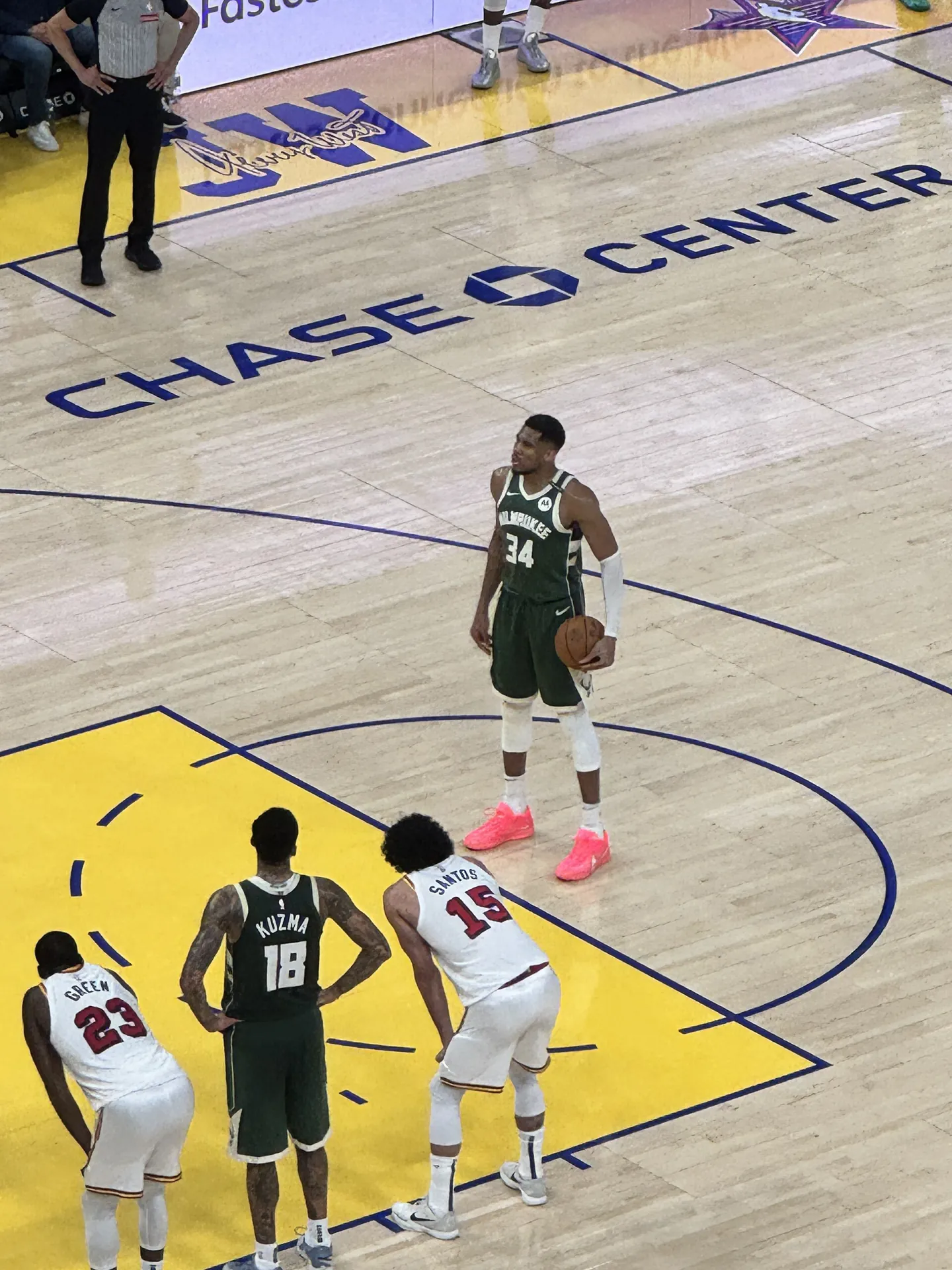 Giannis Antetokounmpo 身穿密爾瓦基公鹿綠色 34 號球衣，在金州勇士主場 Chase Center 的罰球線持球準備罰球，隊友 Kyle Kuzma 與身穿白色球衣的勇士球員在禁區旁等待
