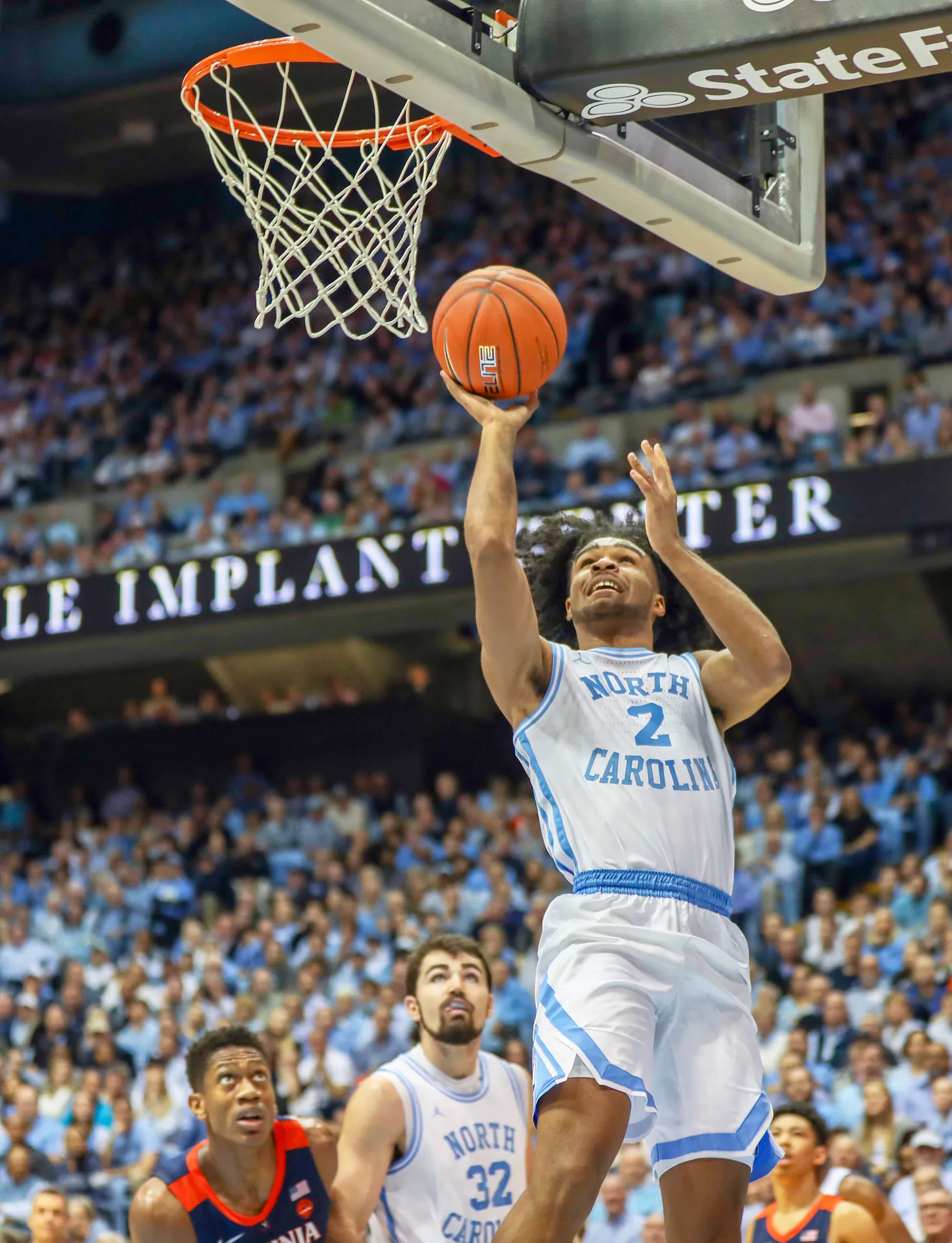 北卡大學 2 號 Coby White 在比賽中單手上籃，維吉尼亞大學球員在籃下抬頭看球