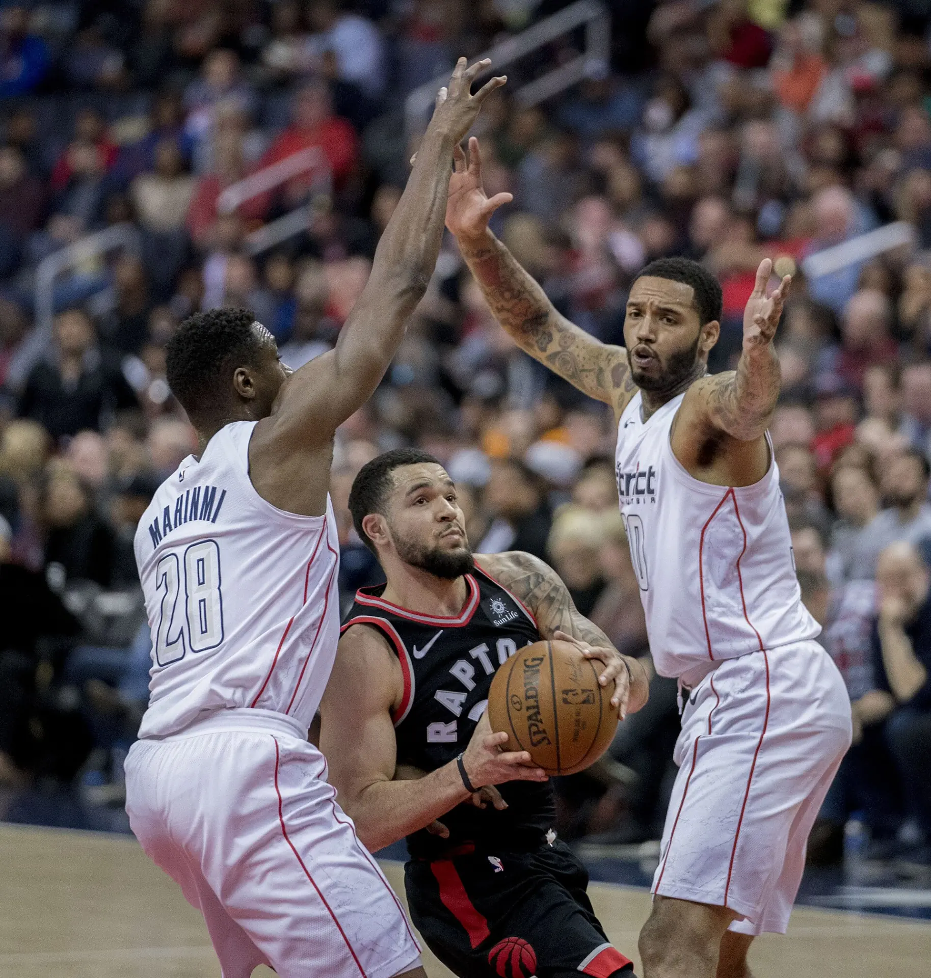 Fred VanVleet 身穿黑色多倫多暴龍球衣，於 NBA 比賽中在兩名華盛頓巫師防守者之間持球突破（攝影 Keith Allison，授權 CC BY-SA 2.0，來源 Wikimedia Commons）