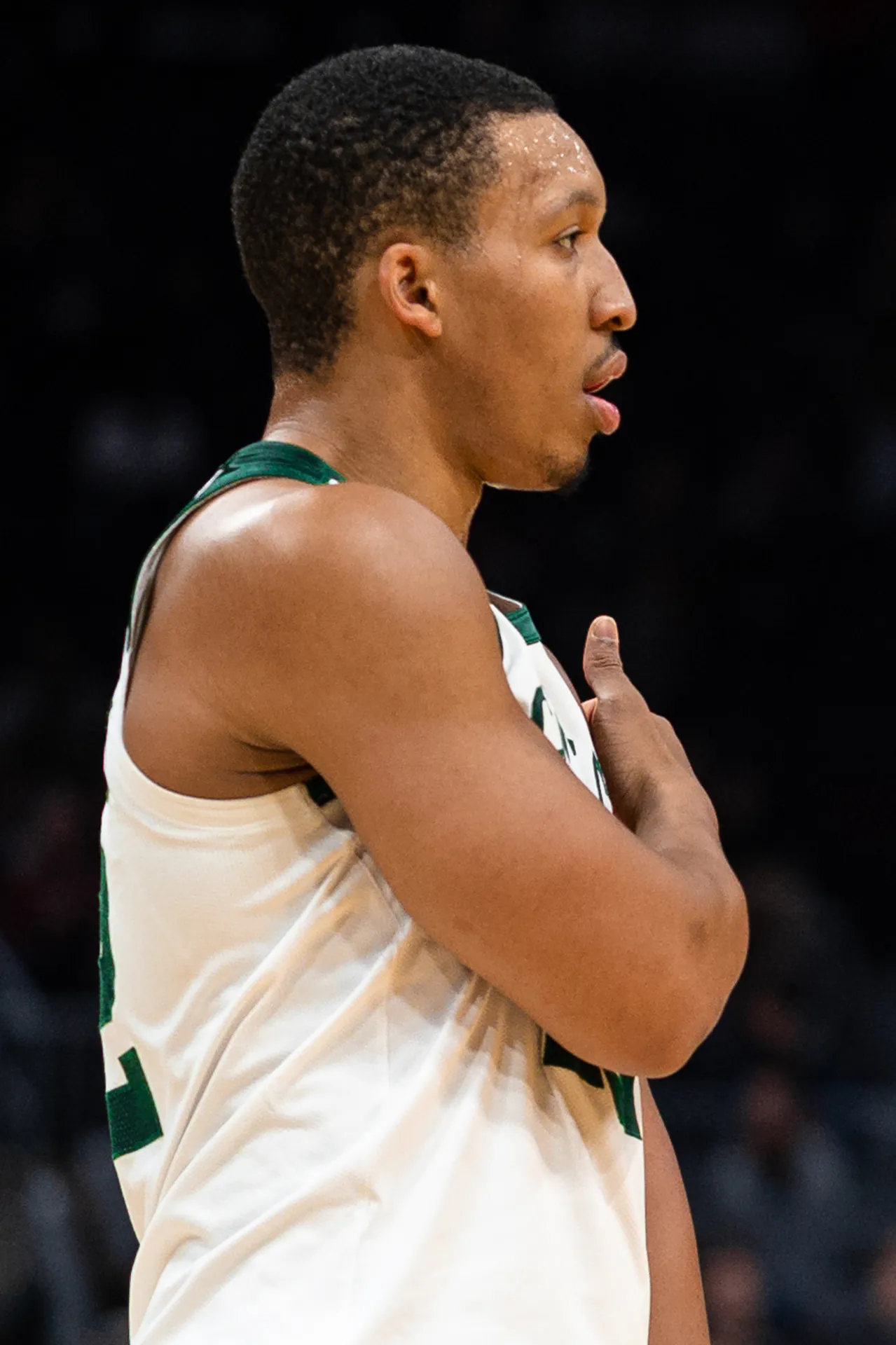 身穿塞爾提克白色球衣的 Grant Williams 在場上側身站立，右手按在胸前
