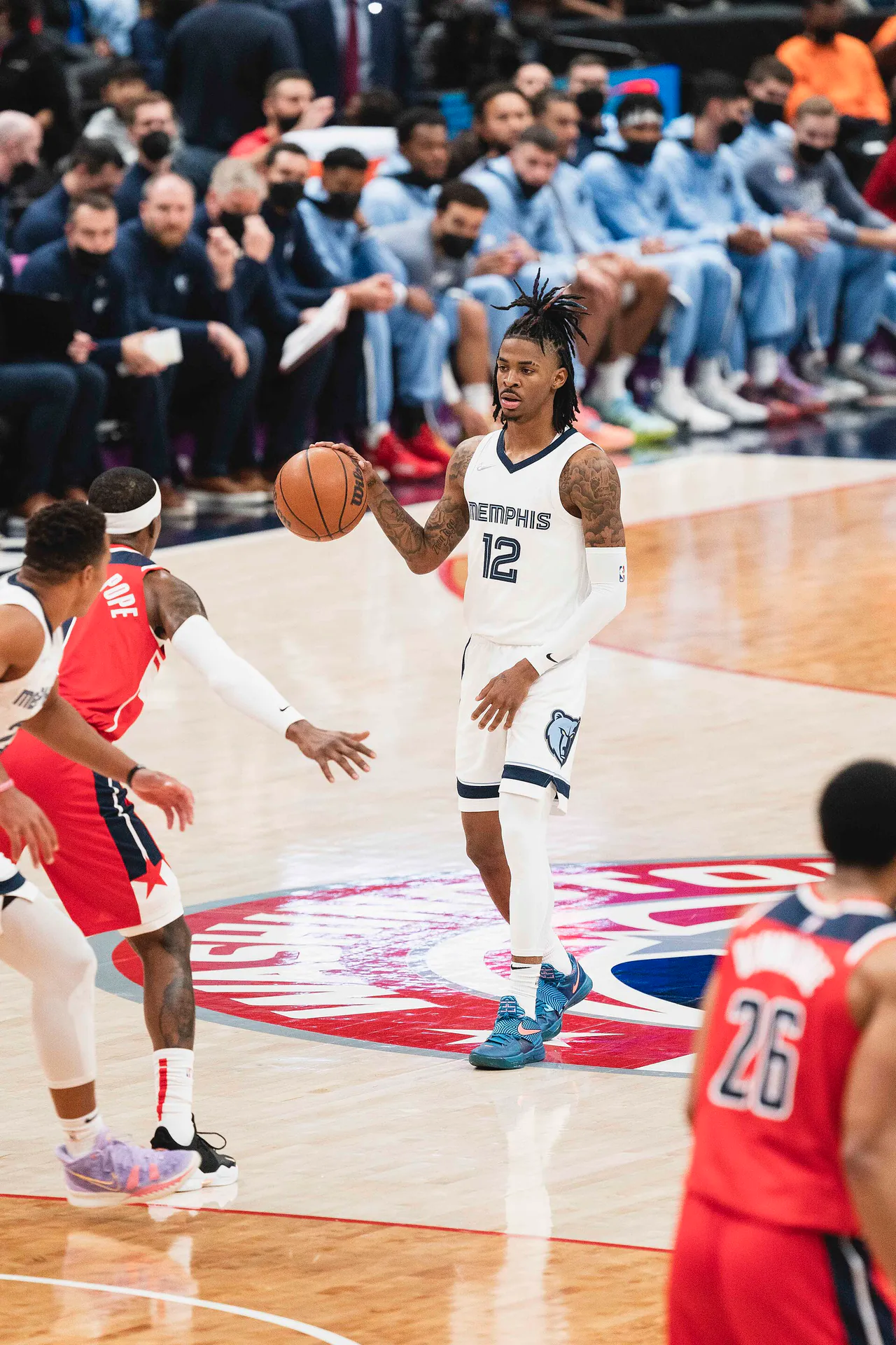 Ja Morant 效力灰熊時期身穿白色 12 號球衣在場上持球推進，對面為巫師球員防守（攝影 All-Pro Reels，授權 CC BY-SA 2.0，來源 Wikimedia Commons）