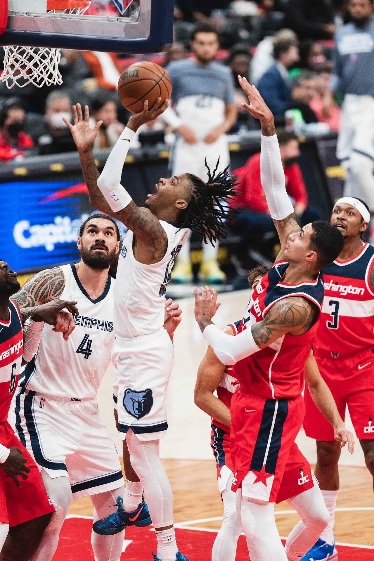 Ja Morant 效力灰熊時期身穿白色球衣騰空上籃，巫師球員舉手封阻，左側為灰熊 4 號 Steven Adams（攝影 All-Pro Reels，授權 CC BY-SA 2.0，來源 Wikimedia Commons）