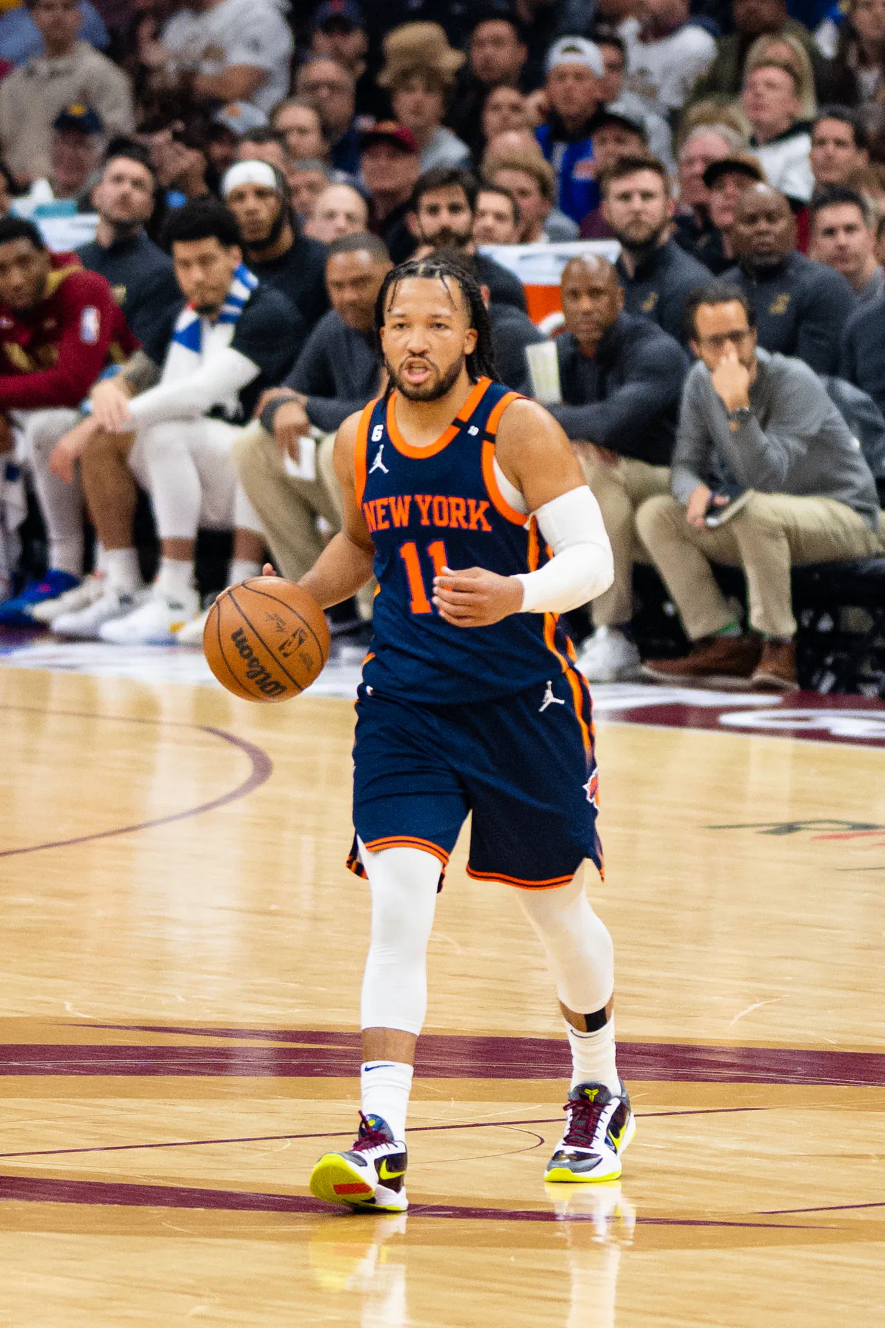 Jalen Brunson 身穿紐約尼克深藍色 11 號客場球衣，2023 年季後賽首輪作客克里夫蘭騎士時在場上運球推進（攝影 Erik Drost，授權 CC BY 2.0，來源 Wikimedia Commons）