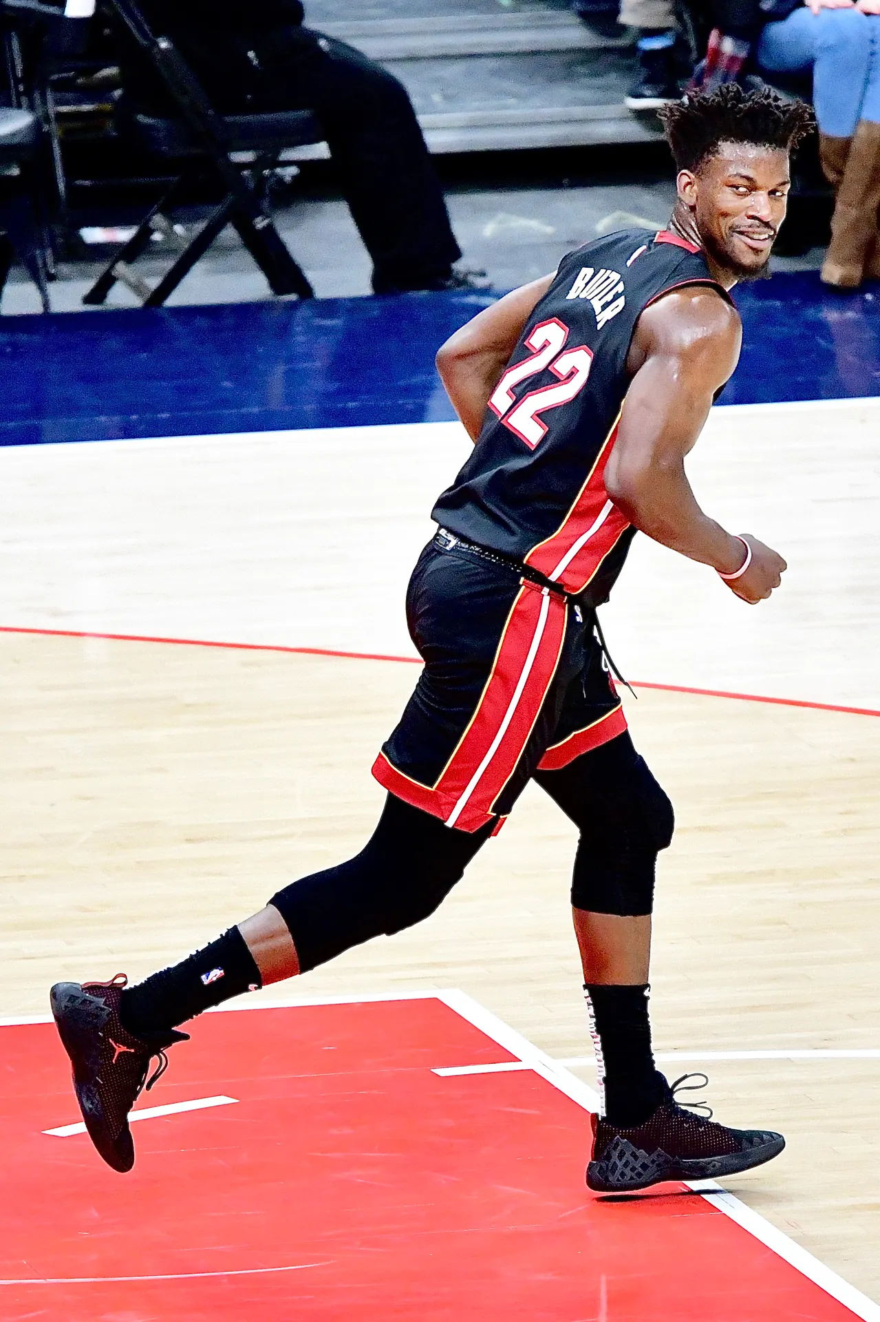 Jimmy Butler 身穿熱火黑色 22 號球衣在場上回防，回頭露出笑容（攝影 Joe Glorioso，授權 CC BY-SA 2.0，來源 Wikimedia Commons）