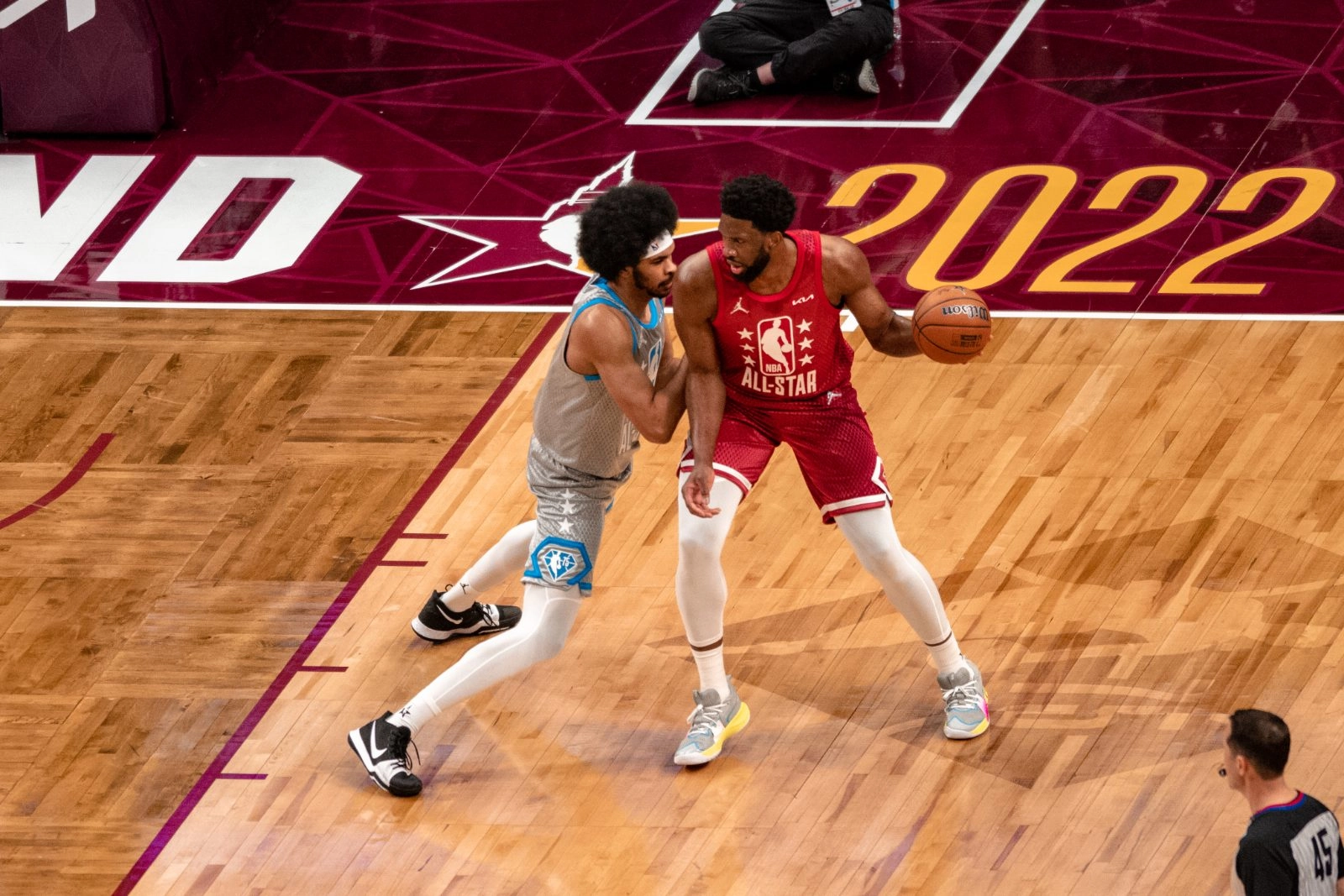 Joel Embiid 身穿紅色 21 號全明星球衣於 2022 年 NBA 全明星賽中背身持球，由 Jarrett Allen 防守。攝影：Erik Drost，授權 CC BY 2.0，來源 Wikimedia Commons。