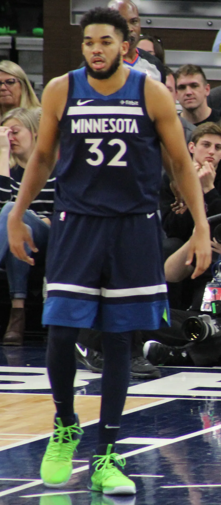身穿灰狼深藍色 32 號球衣的 Karl-Anthony Towns 在比賽中站在場上（攝影 SusanLesch，CC BY 4.0，Wikimedia Commons）