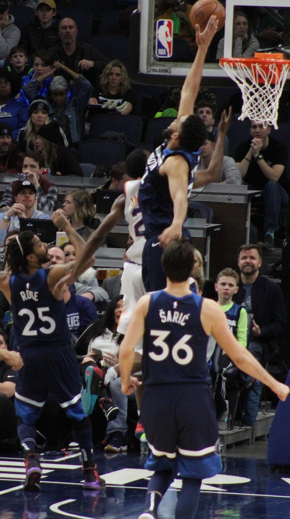 Karl-Anthony Towns 效力明尼蘇達灰狼時期比賽中切入籃下出手，隊友 Rose、Šarić 在旁（攝影：SusanLesch，授權 CC BY 4.0，來源 Wikimedia Commons）