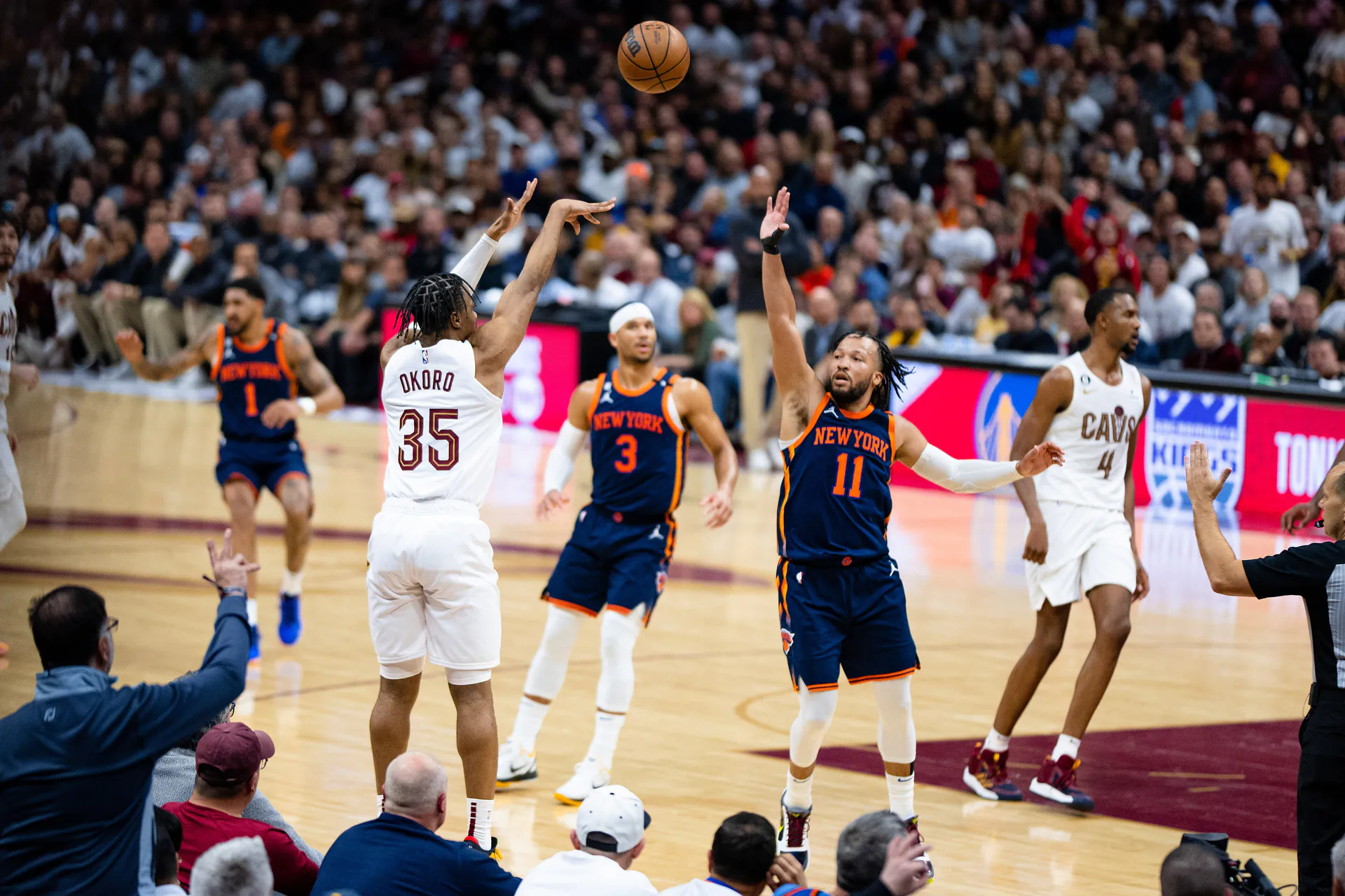 騎士 35 號 Isaac Okoro 出手三分，尼克 11 號 Jalen Brunson 伸手封阻，後方為尼克 3 號 Josh Hart（攝影 Erik Drost，授權 CC BY 2.0，來源 Wikimedia Commons）