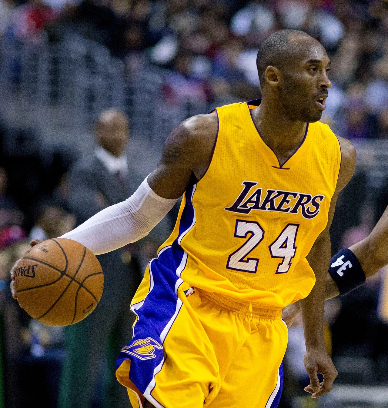 生涯後期的 Kobe Bryant 身穿湖人金色球衣運球推進。攝影：Keith Allison，授權 CC BY-SA 2.0，來源 Wikimedia Commons。