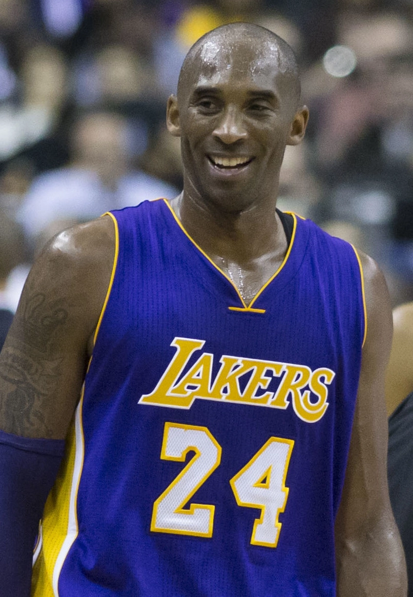 Kobe Bryant 身穿紫色湖人 24 號球衣露出笑容。攝影：Keith Allison，授權 CC BY-SA 2.0，來源 Wikimedia Commons。