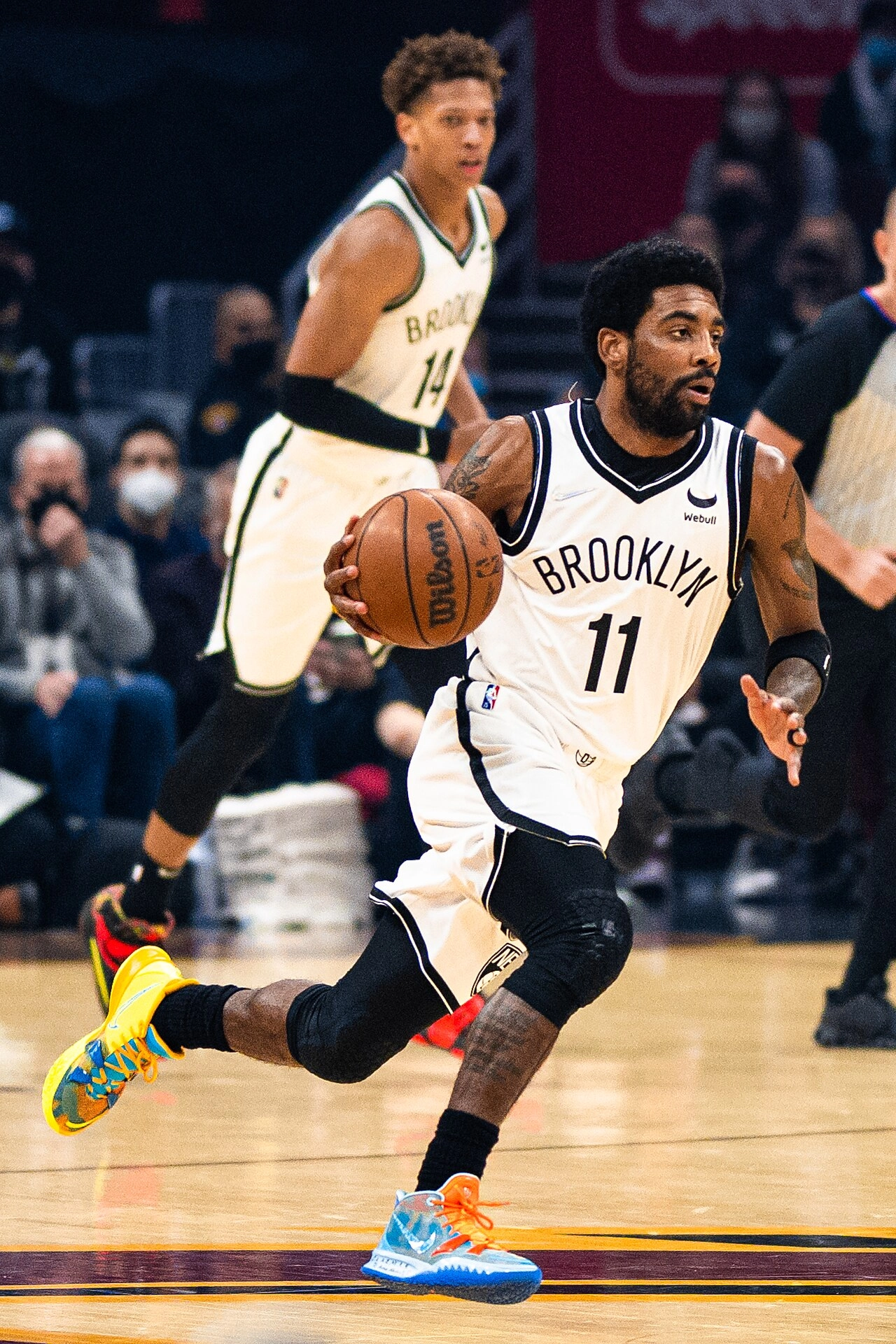 Kyrie Irving 身穿布魯克林籃網 11 號白色球衣，於比賽中運球快速推進。攝影 Erik Drost，授權 CC BY 2.0，來源 Wikimedia Commons