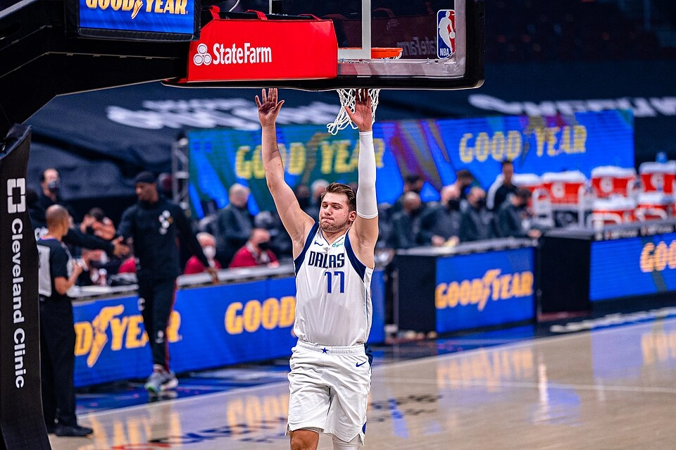 Luka Dončić 效力達拉斯獨行俠時期，身穿白色 77 號球衣於對戰騎士的比賽中舉臂（攝影：Erik Drost，授權 CC BY 2.0，來源 Wikimedia Commons）