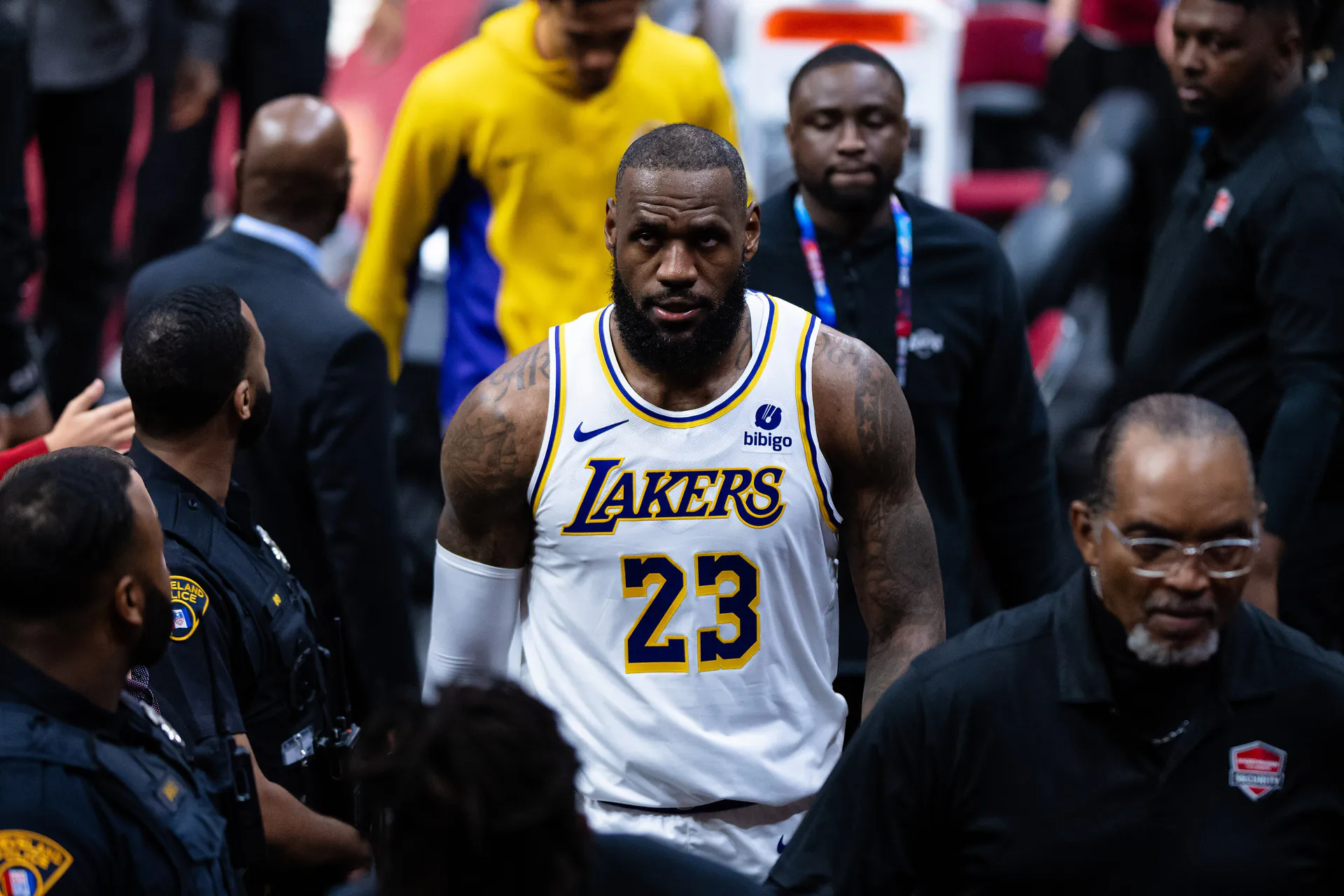 身穿湖人白色 23 號球衣的 LeBron James 在騎士主場賽後於維安人員簇擁下走下球場