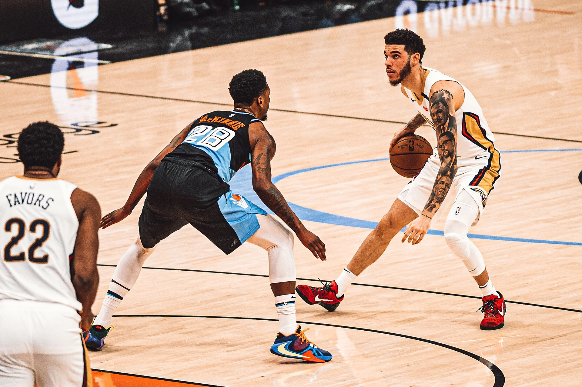 Lonzo Ball 身穿紐奧良鵜鶘白色球衣持球，面對一名深色球衣防守者，隊友 Favors 在旁。攝影：Erik Drost，CC BY 2.0 授權，來源 Wikimedia Commons。