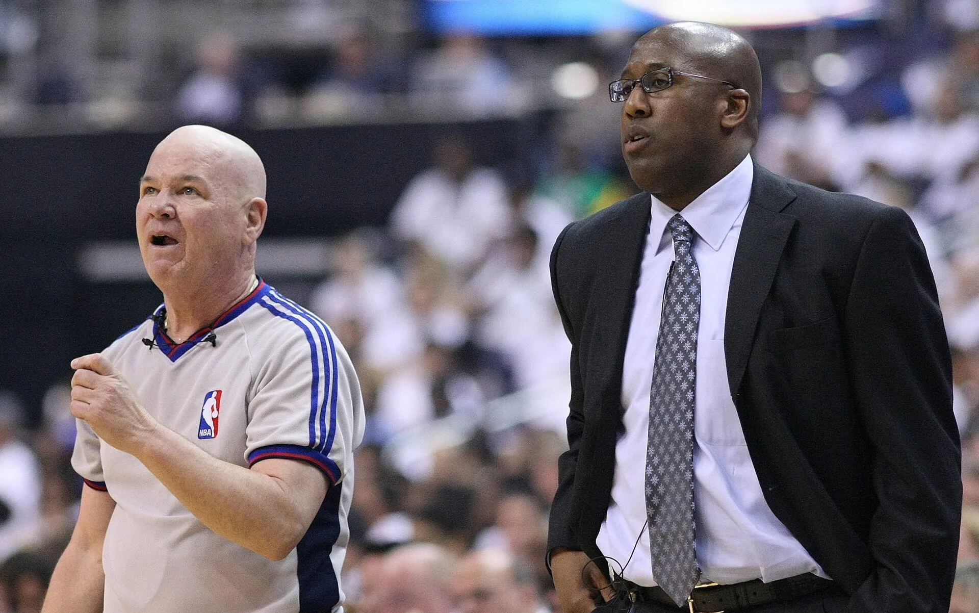 時任騎士總教練 Mike Brown 站在場邊，左為 NBA 裁判，Keith Allison 攝，CC BY-SA 2.0