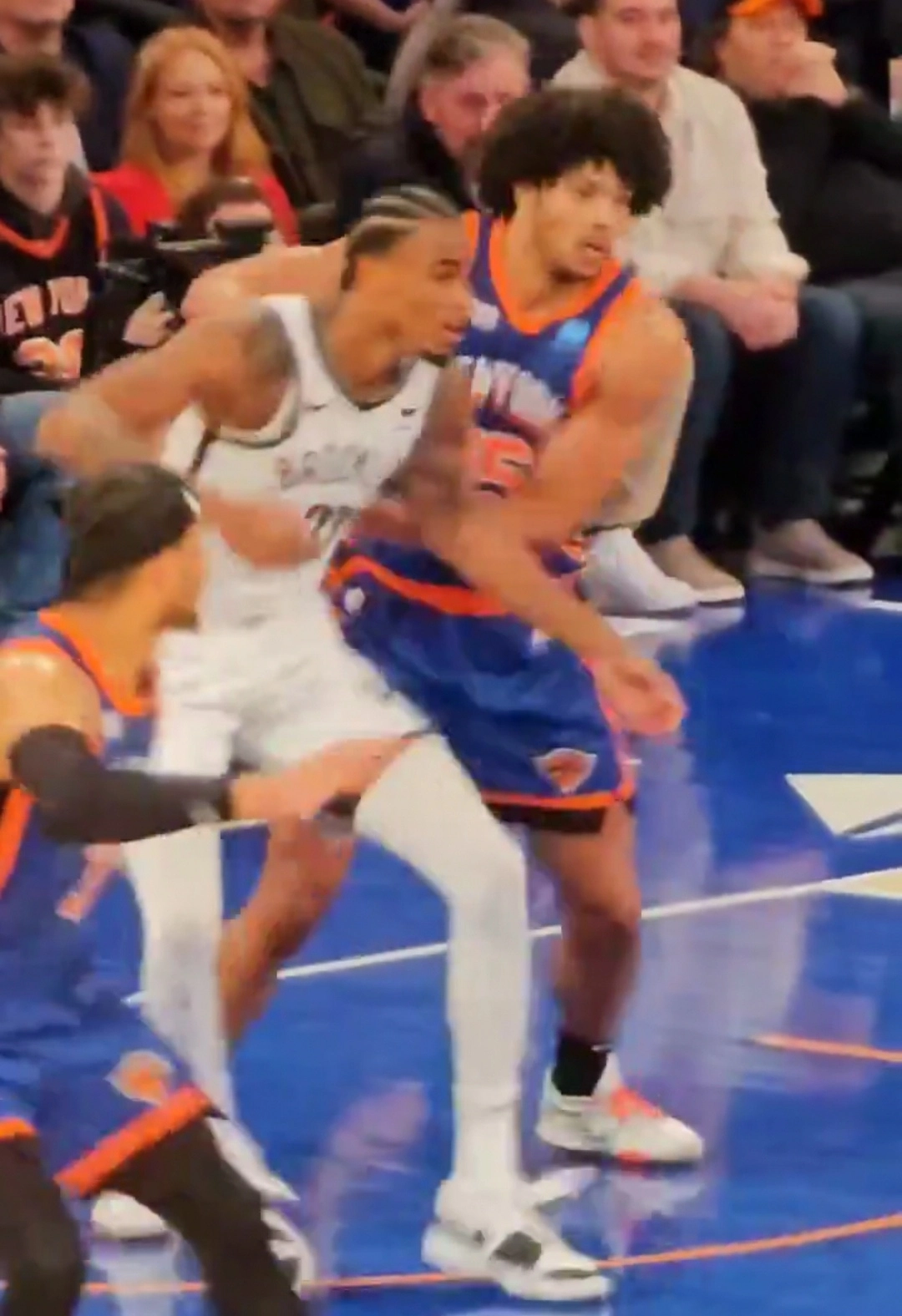 Miles McBride 身穿紐約尼克藍色球衣，於場上與布魯克林籃網白衣球員近身卡位對抗（攝影 Saggittarius A，授權 CC BY 4.0，來源 Wikimedia Commons）