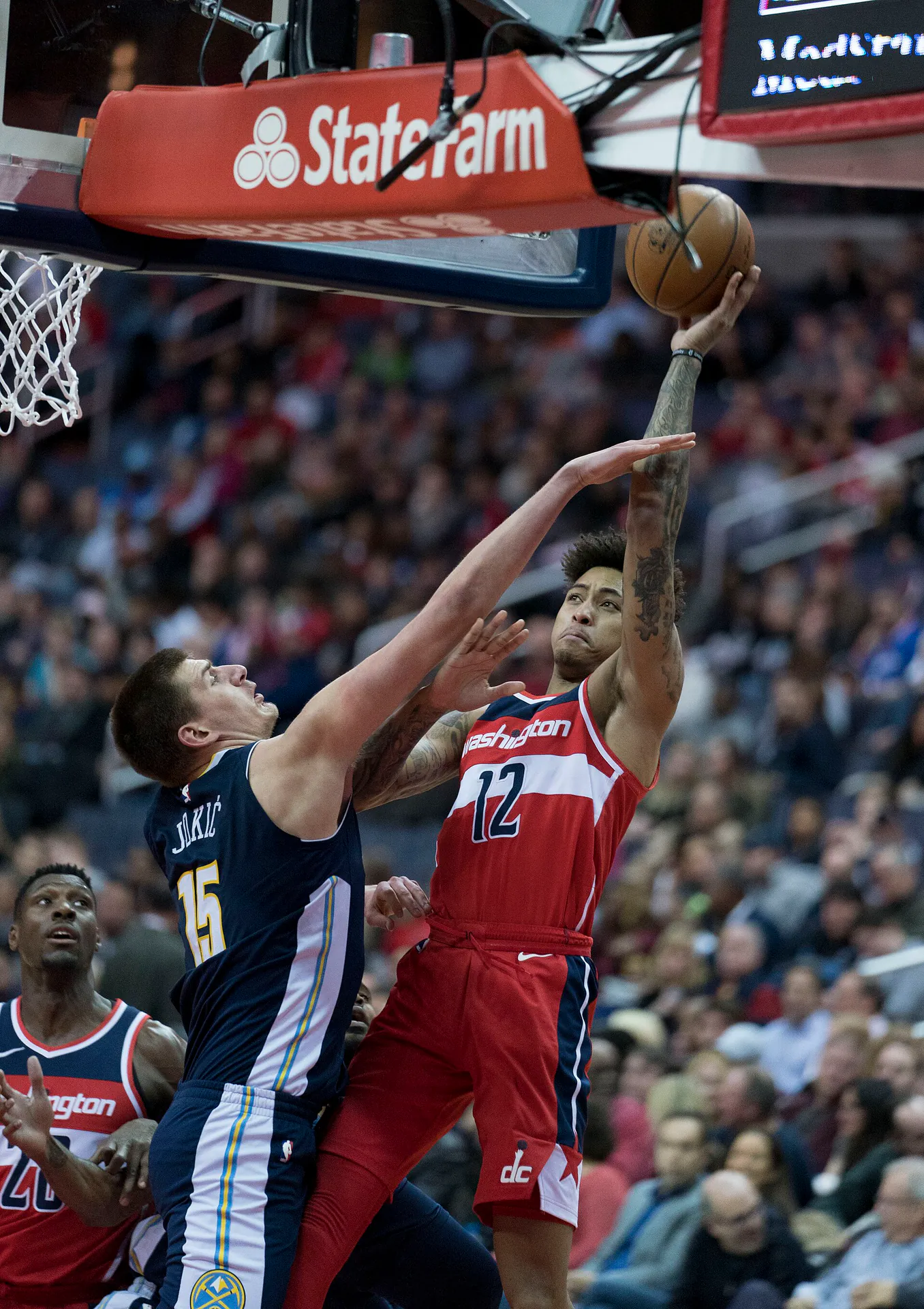 Nikola Jokic 身穿金塊深藍色 15 號球衣，伸手封阻奇才 12 號球員的上籃（攝影 Keith Allison，授權 CC BY-SA 2.0，來源 Wikimedia Commons）