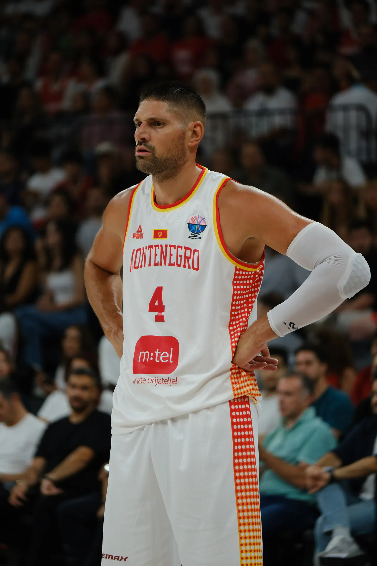 身穿蒙特內哥羅白色 4 號球衣的 Nikola Vucevic 雙手叉腰站在場上