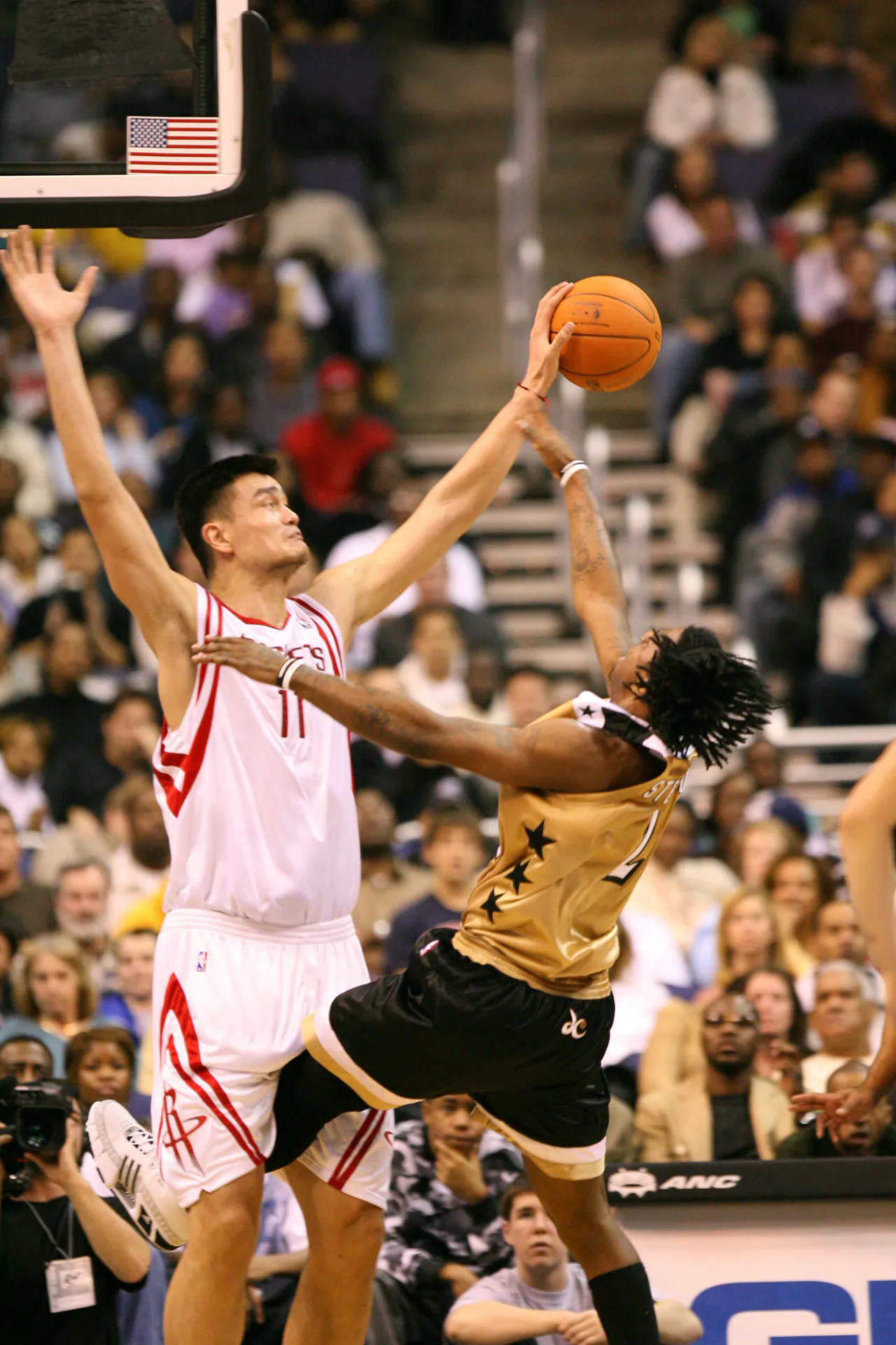 2006 年火箭 Yao Ming 高舉雙手封堵巫師球員出手，攝影 Keith Allison，CC BY-SA 2.0