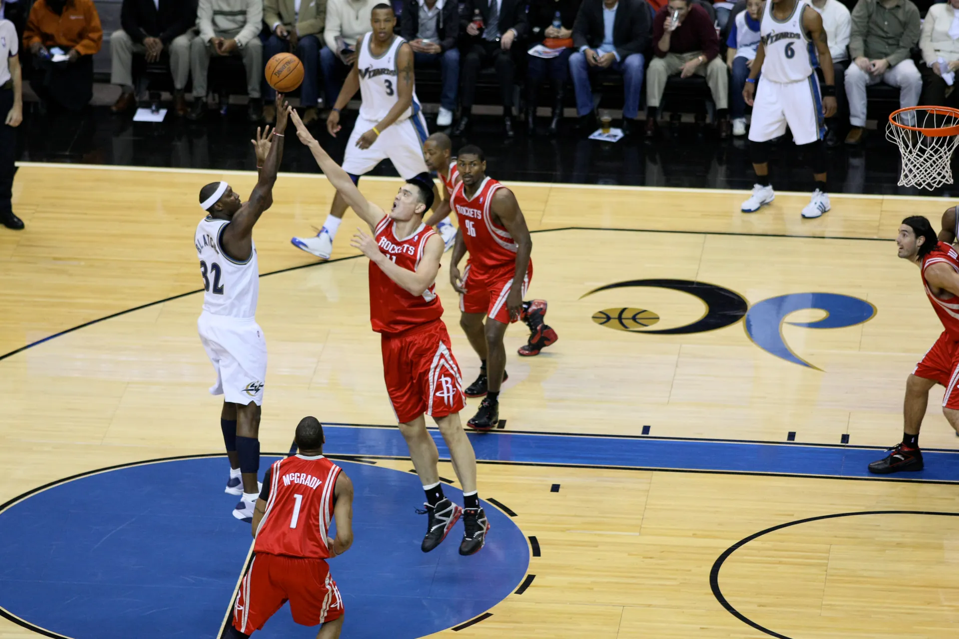 2008 年火箭 Yao Ming 伸手干擾巫師球員跳投，Tracy McGrady 在旁補位，攝影 Keith Allison，CC BY-SA 2.0